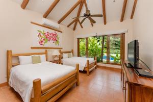 1 dormitorio con 2 camas y TV de pantalla plana en Punta Islita Villas Luxury Destination, en Islita