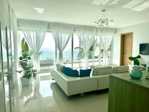 a living room with a white couch and large windows at Sea Winds with Direct Ocean Views in Cabarete