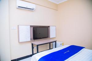 VEGAS LUXURY HOTEL في دار السلام: غرفة بها تلفزيون على الحائط وسرير