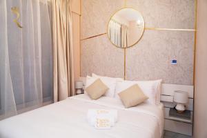 una camera da letto con un letto bianco e uno specchio a parete di Jade Serenity 2BR Urban Hideaway in Oasis a Al Qurayyah