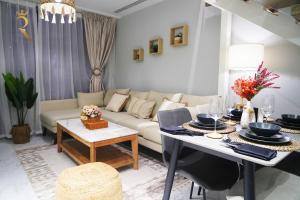 a living room with a couch and a table at 2BR SkyHome at Jade Masdar Oasis in Al Qurayyah