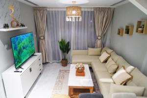 un soggiorno con divano e TV a schermo piatto di 2BR SkyHome at Jade Masdar Oasis a Al Qurayyah