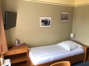 sypialnia z łóżkiem, biurkiem i telewizorem w obiekcie Garni Hotel-Pension Holum w mieście Neuharlingersiel
