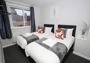 2 bedden in een kamer met witte en oranje kussens bij Must stay 3 Bedroom house near Greenwich and Blackheath- Ideal for families and contractors in Londen