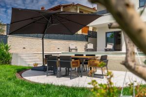 eine Terrasse mit einem Tisch, Stühlen und einem Sonnenschirm in der Unterkunft Villa Cascada in Muntić