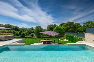 einen Pool mit einem Tisch und einem Sonnenschirm in der Unterkunft Villa Cascada in Muntić