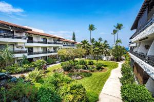 un patio de apartamentos con jardín y palmeras en Casa de Emdeko 202 en Kailua-Kona