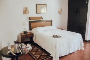 1 dormitorio con 1 cama con manta blanca y mesa en Hotel Ilebal en Cuernavaca