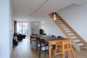 a dining room with a table and chairs and a staircase at Prachtig duplex appartement met balkon te Wenduine in De Haan