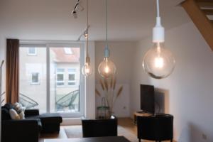 a living room with pendant lights and a table and chairs at Prachtig duplex appartement met balkon te Wenduine in De Haan