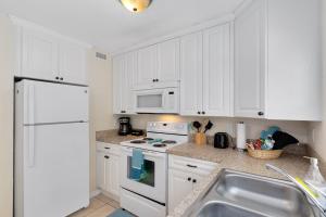 a kitchen with white cabinets and a white stove top oven at Ocean 19 - Tideside in Indian Harbour Beach +31 photos