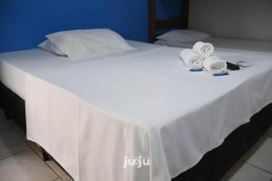 uma cama branca com dois rolos de toalhas em Pousada Ju&Ju à 400 mts DA PRAIA em Pontal do Paraná