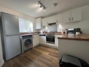 a kitchen with white cabinets and a washer and dryer at Entire House in Littleover Derby in Mickleover