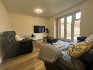 ein Wohnzimmer mit einem Sofa und einem TV in der Unterkunft Entire House in Littleover Derby in Mickleover