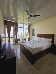 a bedroom with a large bed with a ceiling fan at Tulips Village Resorts in Ooty