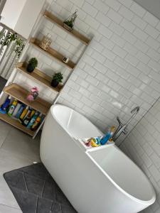 y baño con bañera blanca y azulejos blancos. en Tredegar property, unique location with luxury bedroom, bathroom & dining room en Sirhowy