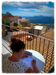 una donna che scrive su una tavola da surf su un balcone di B&b Boladina Experience a Baunei