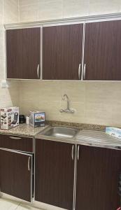 a kitchen with a sink and wooden cabinets at استراحة المسافر in Al Ain