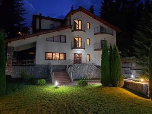 a large white house at night with lights at Casa Cristian in Sinaia