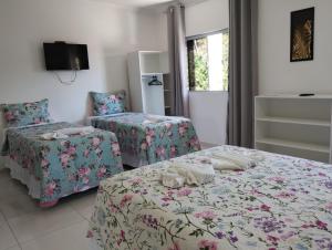 a bedroom with two beds and a tv on the wall at Pousada La Belle in Maragogi