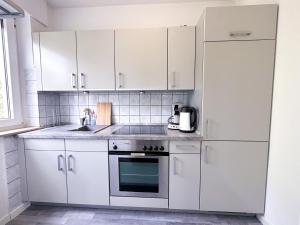a white kitchen with white cabinets and a sink at Stilvolles, frisch renoviertes 2Zi Apartment mit Küche und Balkon in Kliniknähe! in Bad Oeynhausen