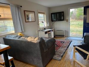 a living room with a couch and a table at Not-so-tiny, Tranquil, Pond front Bungalow in Canaan