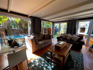 a living room with two couches and a table at Modern Spacious Cottage with Hot Tub, Flora Studio in Hermanus