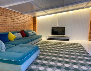 sala de estar con sofá azul y TV de pantalla plana en Duplex 80A, en Tashkent