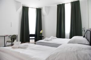 two beds in a room with green curtains and a table at Apartamenty Emilia in Gniezno