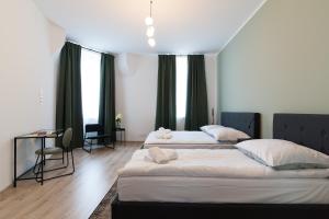 a bedroom with two beds and a table and windows at Apartamenty Emilia in Gniezno