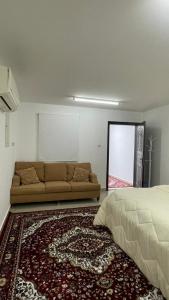 a bedroom with a bed and a couch and a rug at استراحة المسافر in Al Ain