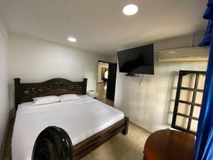 a bedroom with a white bed and a flat screen tv at finca vacacional villa el Resplandor in Dujos