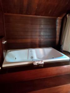bañera blanca en una habitación con pared de madera en Pássaro de Fogo, en Santo Antônio do Pinhal
