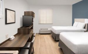 um quarto de hotel com duas camas e uma secretária em WoodSpring Suites Miami Southwest em Kendall