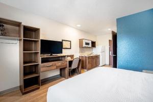 um quarto com uma cama, uma secretária e uma televisão em WoodSpring Suites Miami Southwest em Kendall