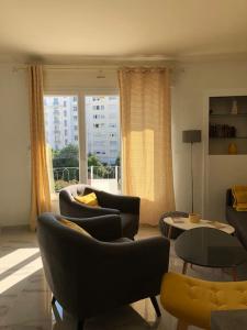 ein Wohnzimmer mit Stühlen, Tischen und einem Fenster in der Unterkunft Appartement chaleureux proche de la croisette in Cannes