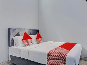 1 dormitorio con 1 cama con almohadas rojas y blancas en Capital O 92765 J&b Smart Sentul en Bogor