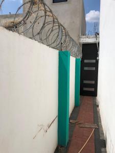 a white wall with a green door and a gate at La casa azul in Culiacán