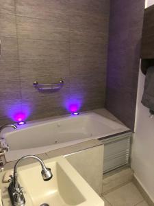 uma casa de banho com uma banheira com luzes roxas em La casa azul em Culiacán