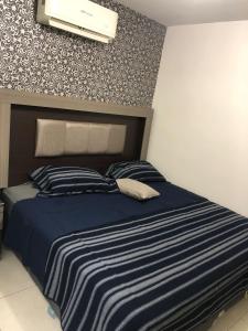 ein Schlafzimmer mit einem Bett mit einer blau-weißen gestreiften Bettdecke in der Unterkunft La casa azul in Culiacán Rosales
