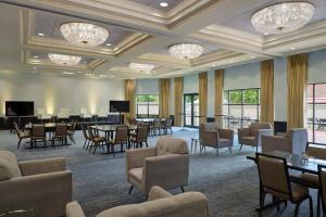 Habitación grande con mesas, sillas y lámparas de araña. en Charlotte Marriott SouthPark, en Charlotte