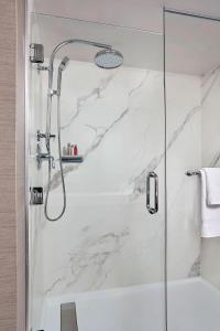 a shower in a bathroom with white marble at Charlotte Marriott SouthPark in Charlotte