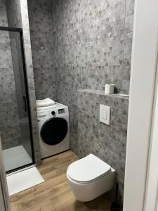 ein Badezimmer mit einem WC und einer Waschmaschine in der Unterkunft Aquarius Kilińskiego 1 in Grodzisk Mazowiecki