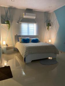 a bedroom with a bed with blue pillows on it at Villa campestre Meqo in Ríohacha
