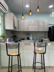 a kitchen with three bar stools in front of a counter at Villa campestre Meqo in Ríohacha