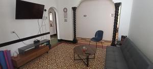 ein Wohnzimmer mit einem TV, einem Tisch und einem Stuhl in der Unterkunft Hostal Casa Azul, doble in Orizaba