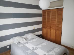 ein Schlafzimmer mit einem Bett und einer gestreiften Wand in der Unterkunft Orteils au soleil jardin parking in Nîmes