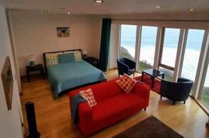 a bedroom with a bed and a red couch at CELLAR COVE in Perranporth