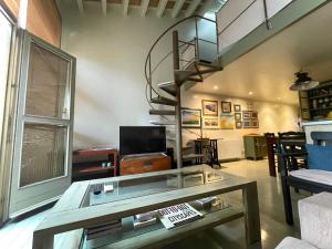 a living room with a glass table and a spiral staircase at Casa/Apartamento Duplex con parking en Palafrugell in Palafrugell