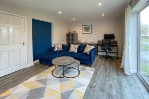 ein Wohnzimmer mit einem blauen Sofa und einem Tisch in der Unterkunft Surrey Hills Lodge in Ewhurst